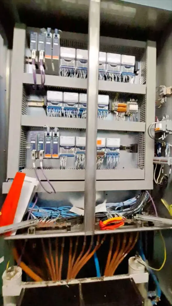 Open switchboard cabinet with breaker rows and wiring looms