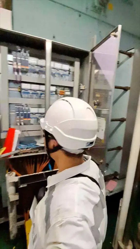 Elektrohertz engineer working at an open control panel aboard a vessel