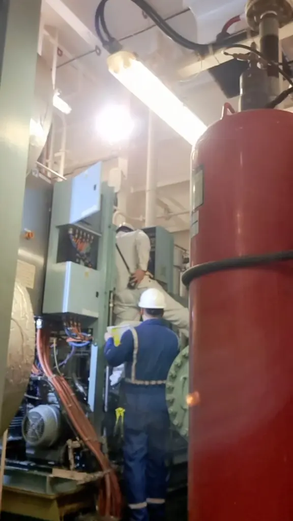 Engineer working in an engine room beside pressure vessels and machinery