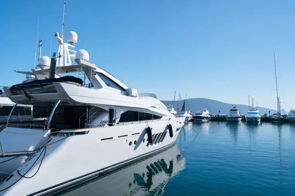 Motor yacht lying alongside in a North Adriatic marina under clear late-morning light, further berths and hills behind.