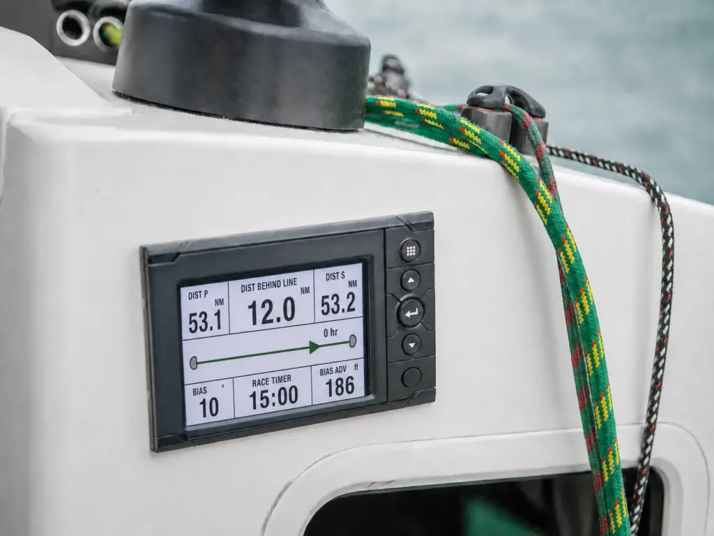 Sailing instrument display set into a yacht's coachroof showing a start-line page with distance to line, race timer and bias readings, winch, rope clutches and halyard alongside