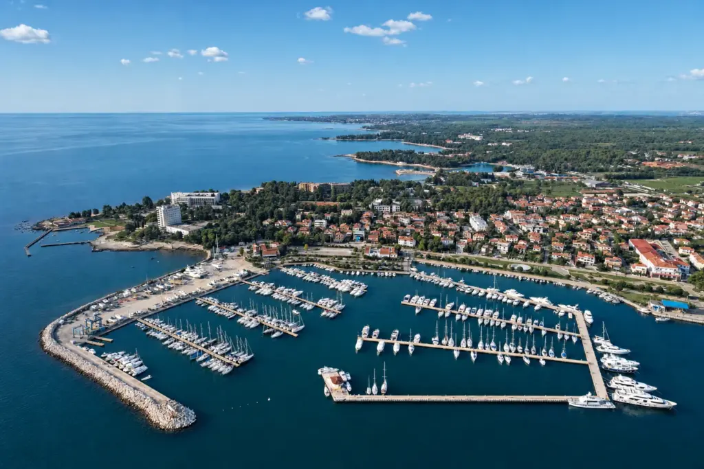 Zračna snimka ACI Marine Umag, plovila na vezu unutar lukobrana, iza njih mjesto i obala